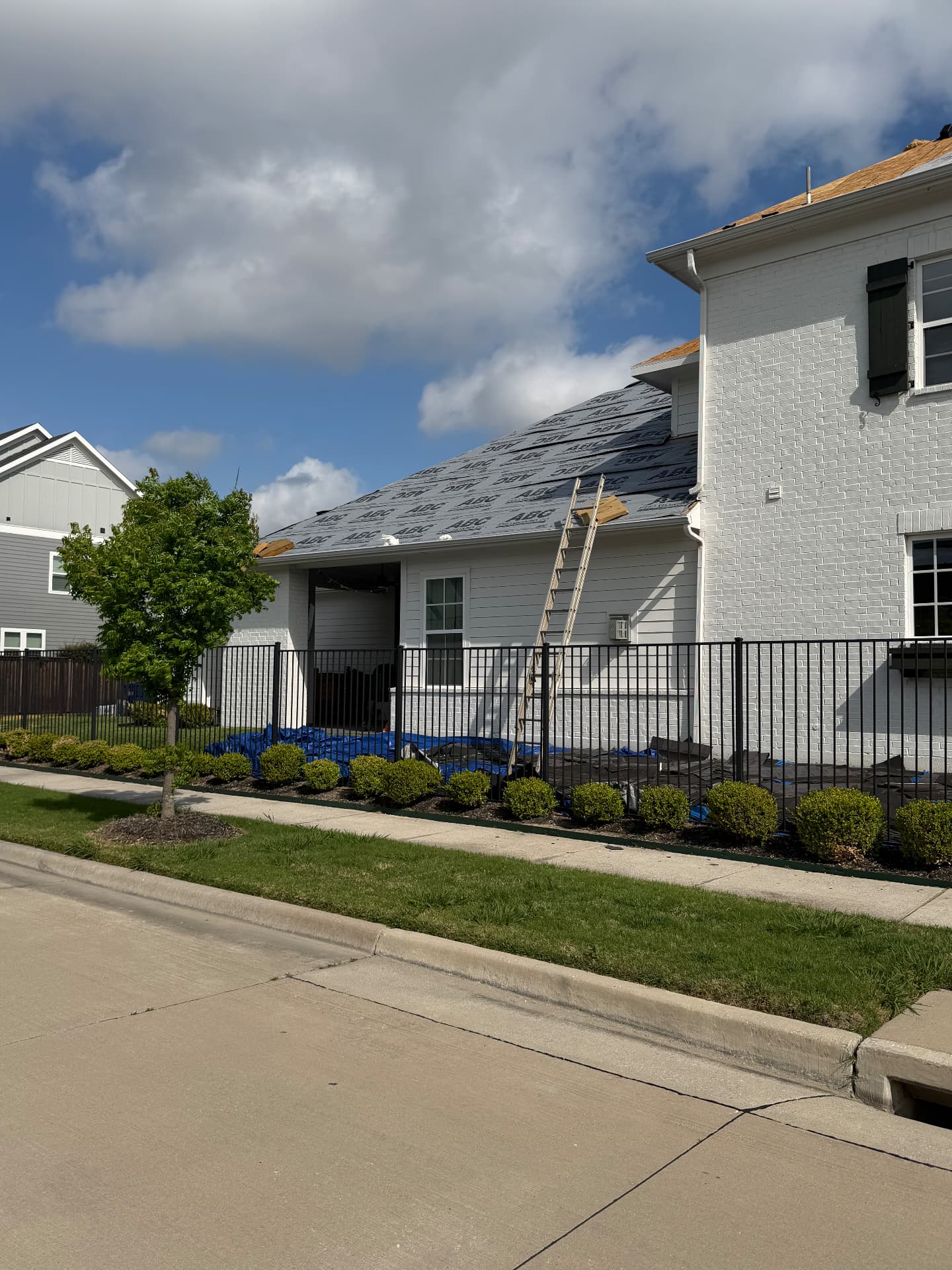 Street-side view of roofing work with a ladder against the home