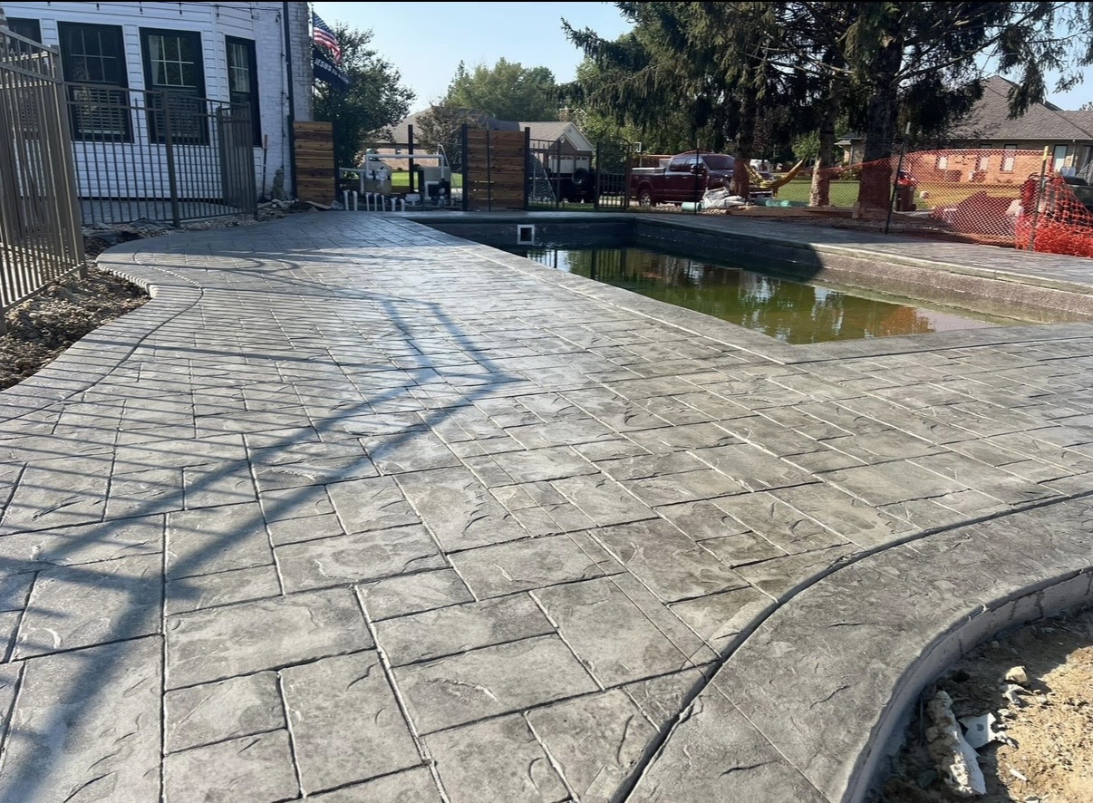 Stamped concrete pool deck with a curved edge and rectangular stone pattern
