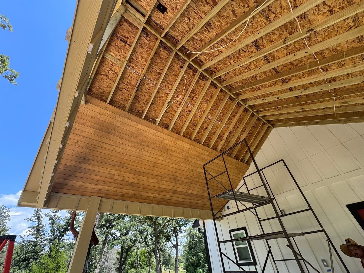 Wood patio ceiling installation beneath exposed roof rafters