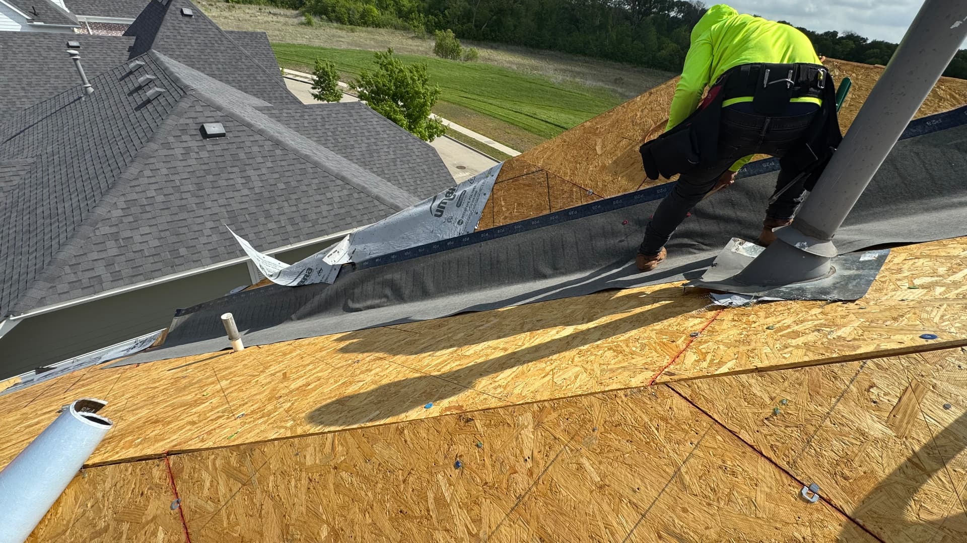 Roofer working beside a roof valley with exposed wood decking and flashing