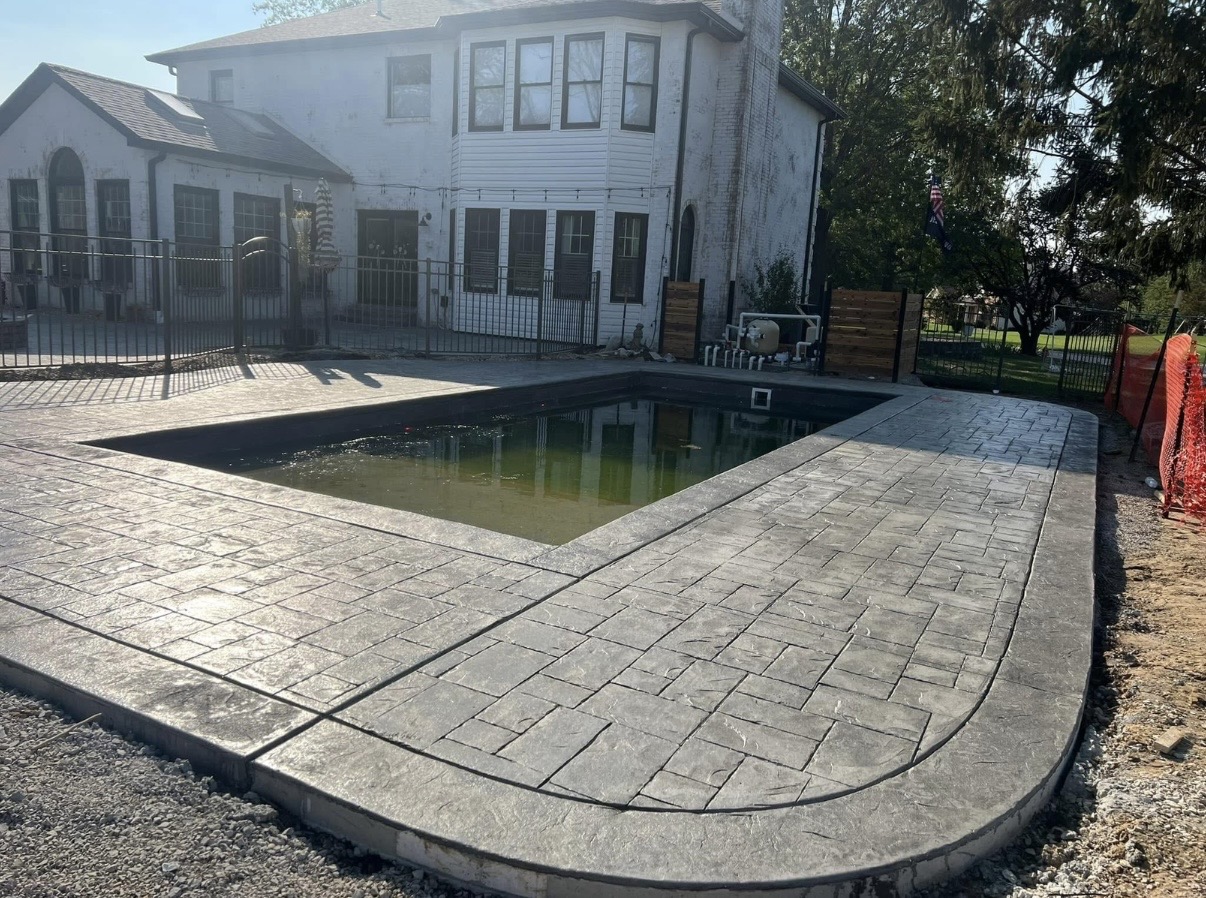 Wide view of stamped concrete surrounding a backyard pool