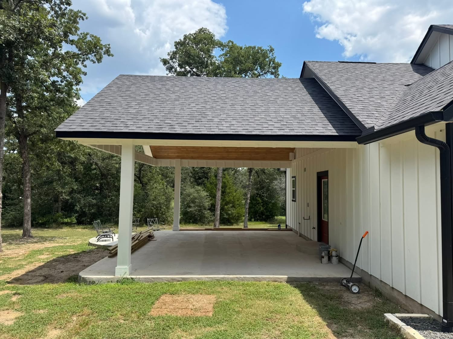Side view of a shingle-roof patio cover attached to a white home