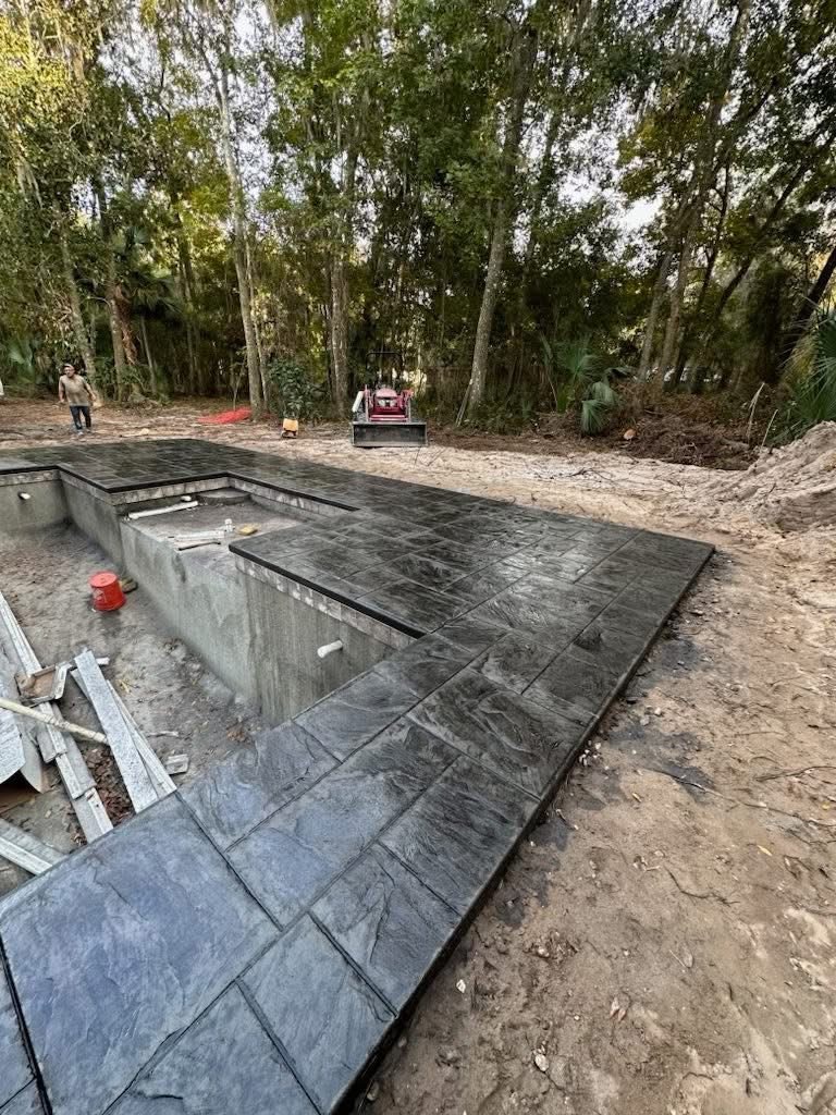 Side view of gray stamped concrete beside a home and pool