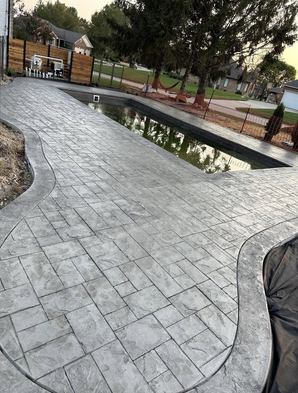Gray stamped concrete paving following the curved edge of a backyard pool