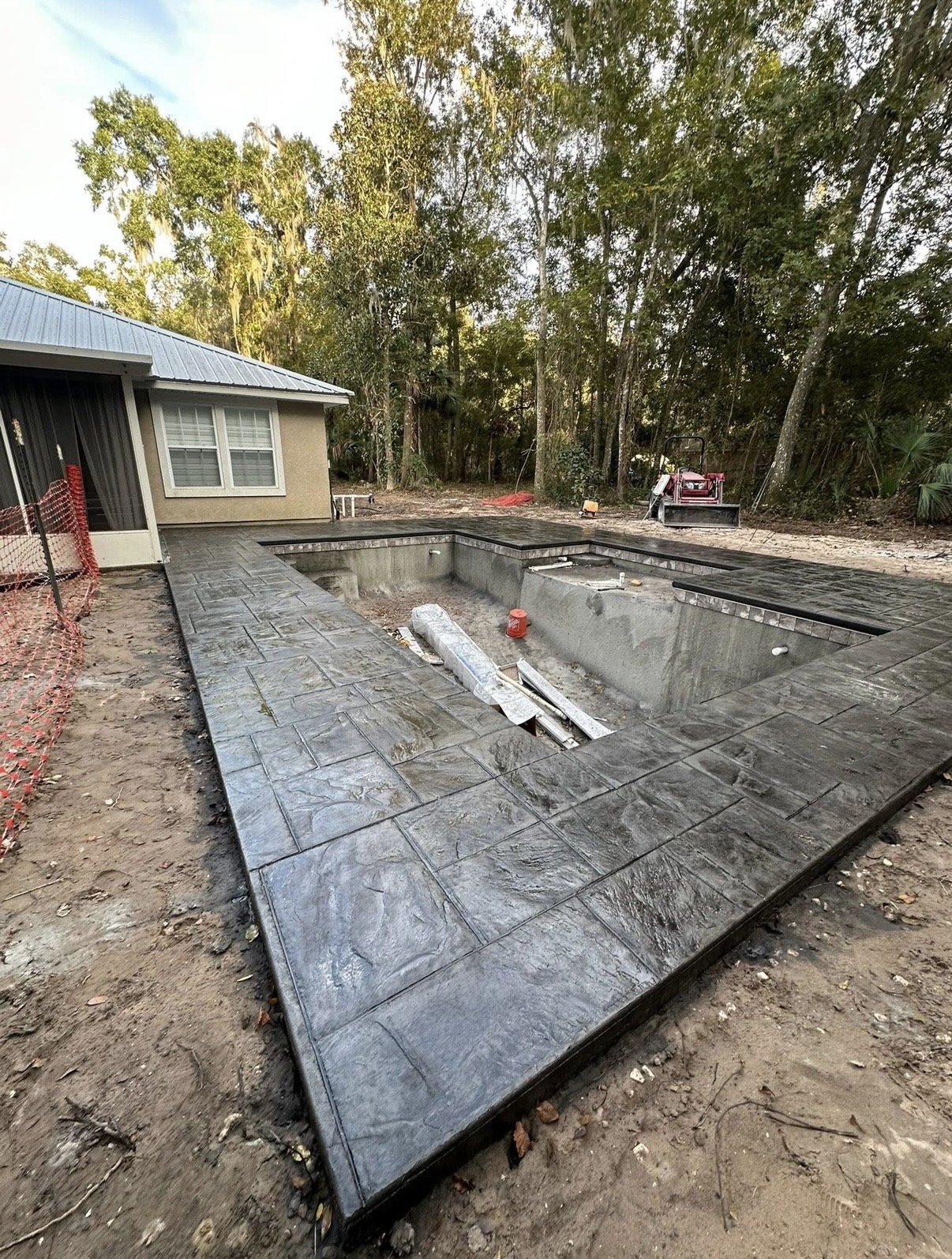 Gray stamped concrete patio with rectangular stone patterns beside a pool