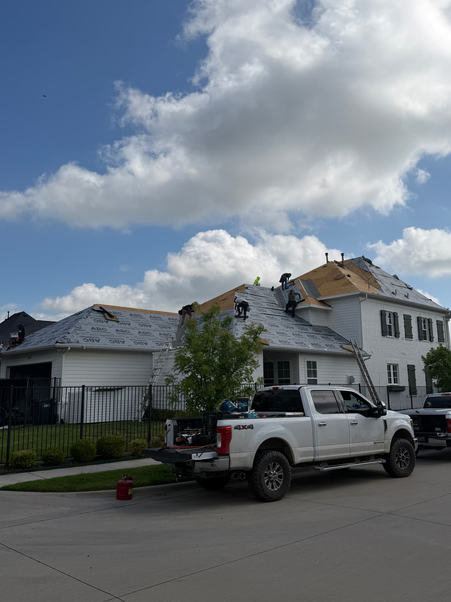 Roofing work on a home viewed from the street with a truck in front
