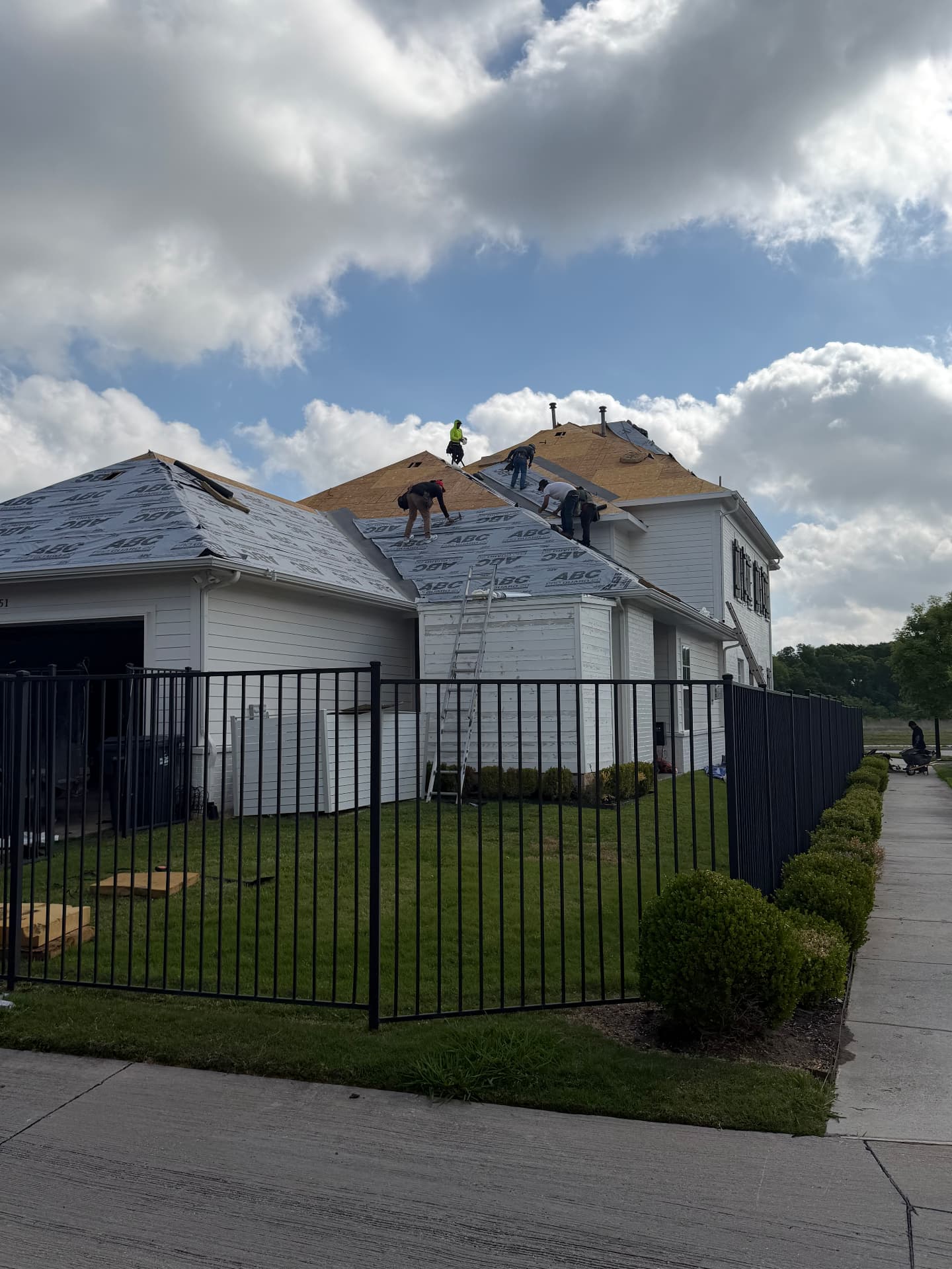 Roof replacement underway above a fenced yard